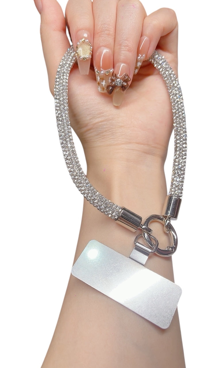 Woman wearing silver rhinestone phone strap with metal clasp on wrist